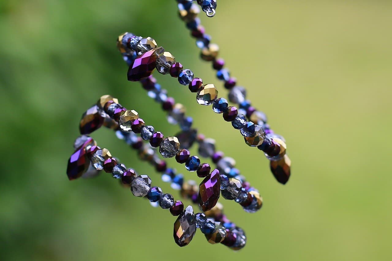 Joyas de color morado sobre un fondo verde con tonos de naturaleza.